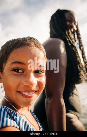 Ragazza sorridente che guarda via con la madre il giorno di sole Foto Stock