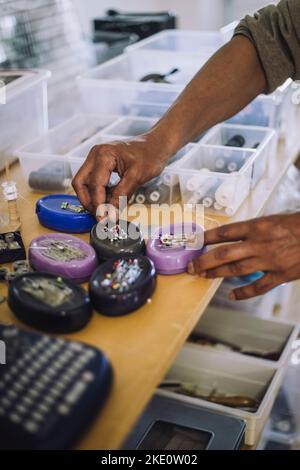 Mani di stilista di moda maschile che raccoglie perni dritti in officina Foto Stock