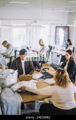 Designer di moda maschili e femminili multirazziali che lavorano insieme in officina Foto Stock