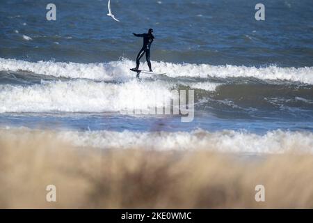 Surfista windsurf in onda spruzzi. L'uomo si sta godendo di sport acquatici in mezzo al mare nelle giornate di sole. Si diverte durante le vacanze estive. Foto Stock