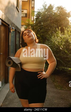 Ritratto di giovane donna fiduciosa con mano sull'anca in piedi nel cortile posteriore Foto Stock