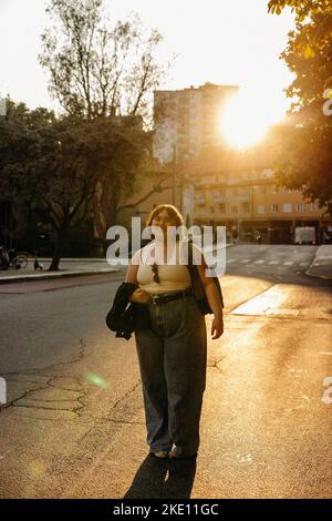 Ritratto di giovane donna sorridente in piedi sulla strada durante il tramonto Foto Stock