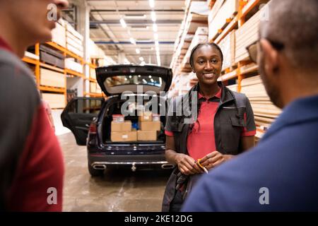 Personale di vendita sorridente che parla con il cliente in magazzino Foto Stock