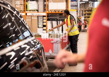 Vista laterale del personale di vendita femminile che scansiona i materiali di consumo attraverso il lettore di codici a barre al banco cassa Foto Stock