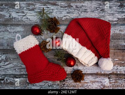 cappello di natale e calza decorativa in lana su sfondo rustico Foto Stock