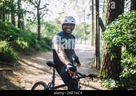 Ritratto di un uomo sorridente appoggiato in bicicletta sul sentiero Foto Stock