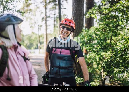 Ciclista maschio felice che parla con l'amico femmina anziano Foto Stock