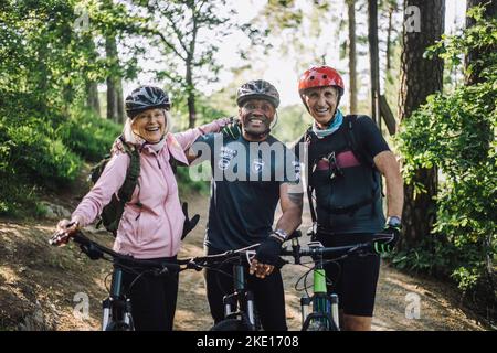 Ritratto di felici amici maschili e femminili con cicli in piedi sul sentiero Foto Stock