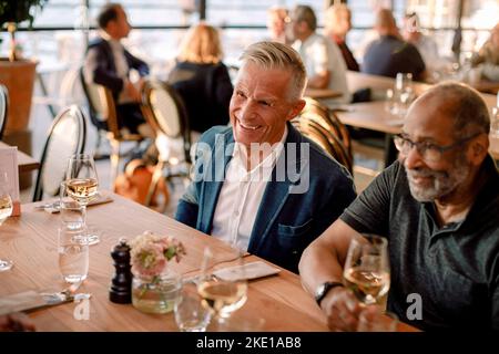 Felice uomo anziano seduto da un amico maschio nel ristorante Foto Stock