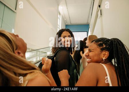 Ritratto di felice ragazza adolescente in piedi da amici femminili ridendo in centro commerciale Foto Stock