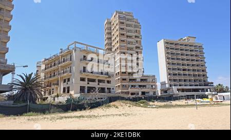 Spiaggia di Famagosta occupata e sorvegliata da soldati turchi di fronte al bombardamento di alberghi vuoti sulla spiaggia. Foto Stock