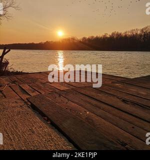 Una banchina di legno su un lago tranquillo durante un bellissimo tramonto Foto Stock