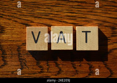 IVA, acronimo di Value Added Tax in lettere alfabetiche di legno isolate su sfondo di legno a trama Foto Stock