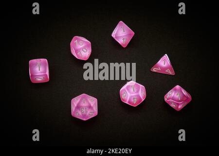 7 dadi poliedrici rosa utilizzati per i giochi di ruolo da tavolo Foto Stock