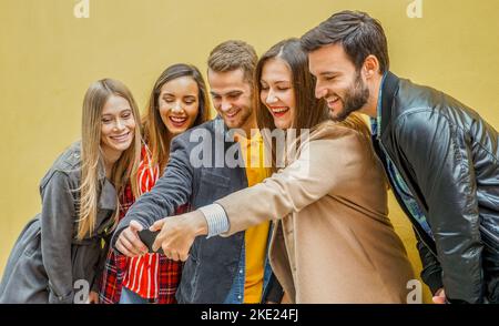 Giovani che usano gli smartphone - Gruppo di social media co-lavoratori che si divertono e si divertono con un selfie - ossessionati da un momento di vita online e di condivisione Foto Stock