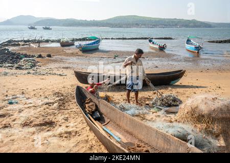 02-16-2022 Goa, India. Pescatori - un uomo e una donna (madre e figlio), svelare la rete inquinata da pesca e sorridere, preparare la rete per il prossimo pesce Foto Stock