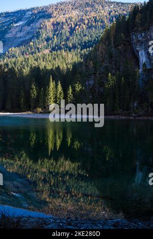 Le acque cristalline del Lago di Tovel, Trentino Alto Adige, Italia. Vista autunnale con riflessi, scatto verticale. Foto Stock
