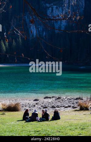 Alcune persone, non riconoscibili, si siedono vicino alle acque cristalline del Lago di Tovel, Trentino Alto Adige, Italia. Scatto verticale. Foto Stock