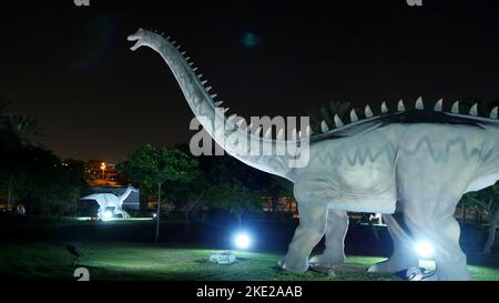 Parco dei dinosauri al Dubai Garden Glow Park, illuminato di notte. Molti dinosauri diversi, sembrano vivi. Foto di alta qualità Foto Stock