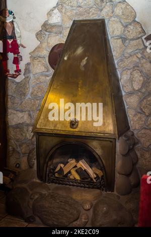 Il fuoco è illuminato in metallo camino con porte in vetro nel soggiorno della casa di campagna. Concetto di camino con fuoco a casa. Primo piano del fuoco nel caminetto Foto Stock