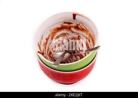 Ciotole vuote per budino di cioccolato con due cucchiai da tè su sfondo bianco. Foto Stock