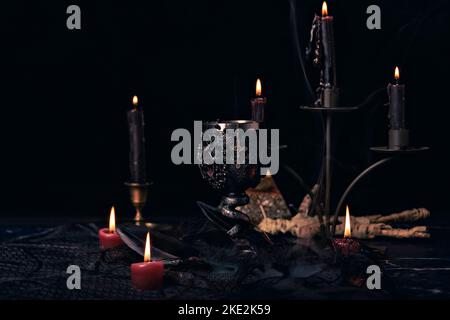 Composizione stregoneria con candele, libri, gioielli e pentagramma simbolo, concetto occulto, rituale magia nera Foto Stock