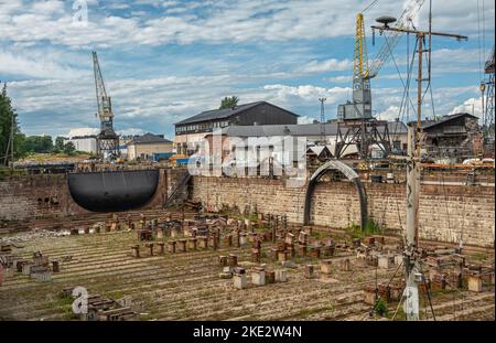 Helsinki, Finlandia - 19 luglio 2022: Fortezza di Suomenlinna. Molo a secco Viaporin presso il cantiere navale con porta con serratura nera. Gru ed edifici industriali sul retro, Foto Stock