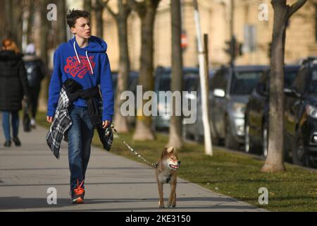 Giovane uomo che cammina il suo cane in Piazza del Re Tomislav (Trg Kralja Tomislava) durante l'inverno. Zagabria, Croazia Foto Stock