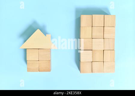 Comprare condominio unità contro casa e concetto di lotto. Costruzione di blocchi di legno e modello di casa. Foto Stock