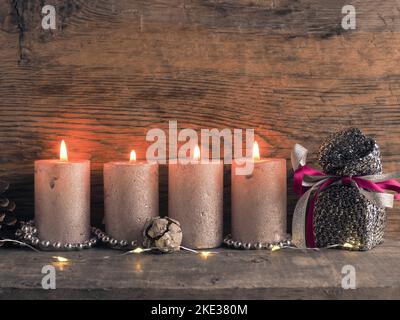 Candela del quarto Avvento bruciature, coni di pino e decorazione di Natale su legno con luci di Natale Foto Stock