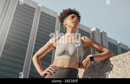 Donna nera, City Fitness e cuffie musicali per la motivazione sportiva, l'esercizio fisico e l'allenamento in città dal basso. Focus, atleta forte e sano Foto Stock