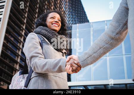 Ritratto di una giovane donna ispanica che scuote le mani. Gli uomini d'affari si stringono a mano in un edificio moderno. Messaggio di saluto Foto Stock