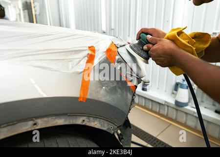 Primo piano del pulitore auto lucidare i fari con lucidatrice Foto Stock