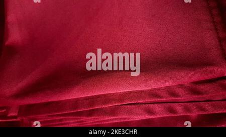 Cucitura su tessuti maroon. Filo con cuciture in tessuto Bordeaux, sfondo tessile. Una pila di tovaglioli tessili. Primo piano Foto Stock