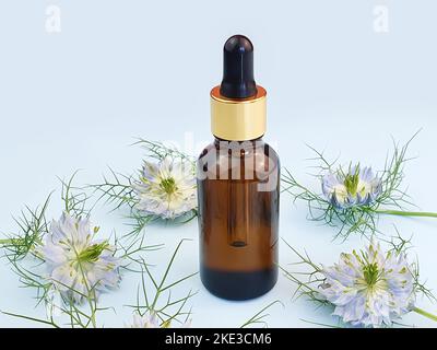 Siero in flacone di vetro marrone senza marchio con pipetta, bordo rotondo di fiori di Nigella blu su sfondo blu. Bianco per bottiglie cosmetiche con ialurone Foto Stock