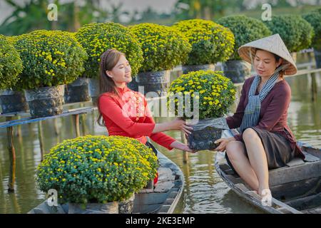 Ho Chi Minh City, Vietnam: Due belle ragazze vietnamite nel giardino del crisantemo che si preparano ad accogliere il tradizionale Capodanno Foto Stock