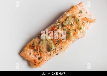 Vista dall'alto di un isolato filetto di salmone al limone con aglio e prezzemolo su un elegante sfondo bianco. Ricette di pesce sane. Foto Stock