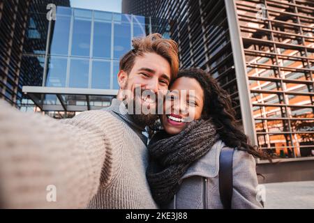 Giovane uomo e donna turista fare selfie e sorridere alla macchina fotografica. Ragazzo e ragazza che si divertono all'aperto facendo un ritratto con lo smartphone Foto Stock
