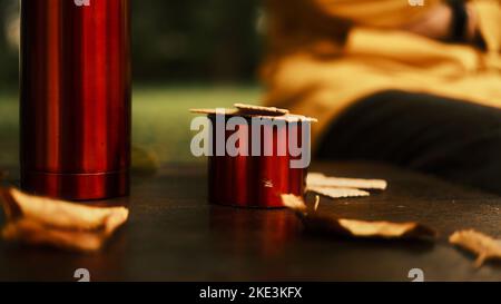 Thermos, tazza di tè e foglie autunnali su un vecchio tavolo di legno Foto Stock