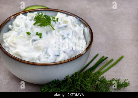 Fresco preferito greco, Tzatziki fatto con cetriolo, yogurt ed erbe aromatiche. Su una superficie grigia chiazzata con spazio di copia Foto Stock