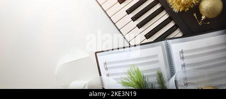 Sottofondo musicale corale natalizio con pianoforte e decorazione natalizia su tavolo bianco. Vista dall'alto. Foto Stock