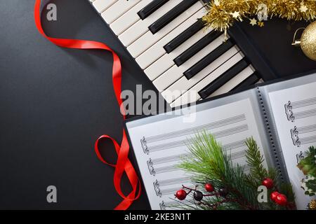 Sottofondo musicale corale natalizio con pianoforte e decorazione natalizia su tavolo nero. Vista dall'alto. Foto Stock