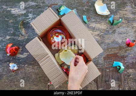 Una donna ha ricevuto un pacco con palle di vetro rotte dell'albero di Natale. Il concetto di un cattivo imballaggio delle merci. Foto Stock