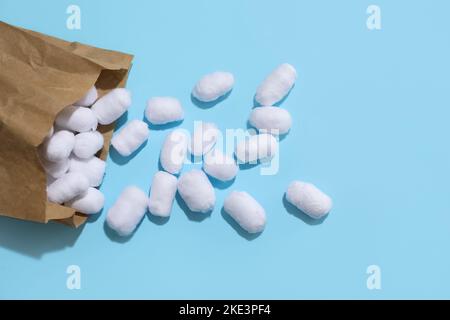 Sacchetto di carta con palle di cotone su sfondo blu Foto Stock