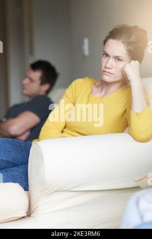 Una giovane coppia infelice seduta sul divano a casa dopo una lotta. Foto Stock