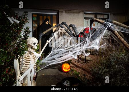 Una casa scozzese che celebra Halloween con un gigantesco ragno e scheletro decorazione. Foto Stock