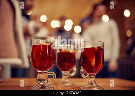 Bicchieri di vino mulled invernale con spezie e fette d'arancia su tavola di legno con decorazioni natalizie. Vita morta con la bevanda tradizionale Foto Stock