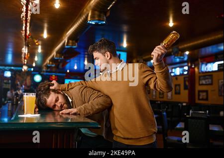 Tifosi di calcio che combattono allo sport bar, ragazzo attacca amico Foto Stock