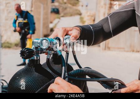 Un maschio che regola la pressione delle bombole di gas con valvole, per l'allenamento subacqueo Foto Stock