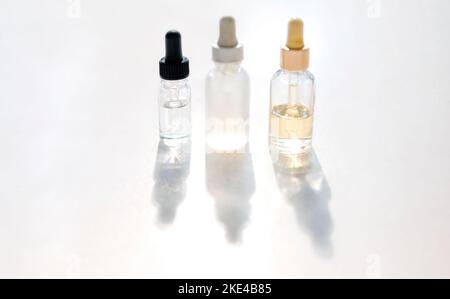 Siero con collagene e peptidi in flaconi di vetro colorati su sfondo chiaro con ombra solare. Essenza per la cura della pelle per una pelle bella e sana. Foto Stock